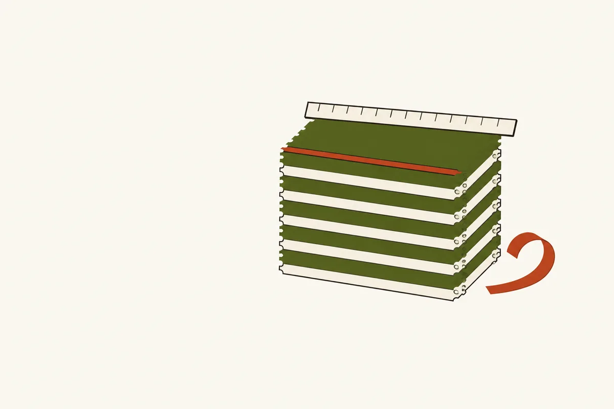 A stack of slips with a ruler along its top edge and one thin slice shaved off and curled beside it.